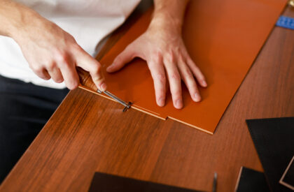 Man using special knife or cutter while processing leather workpiece